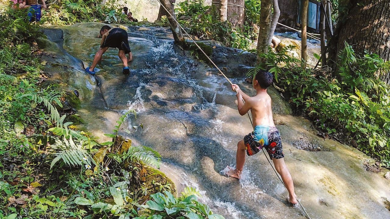 Northland guests climbing the Sticky Waterfall holding a rope