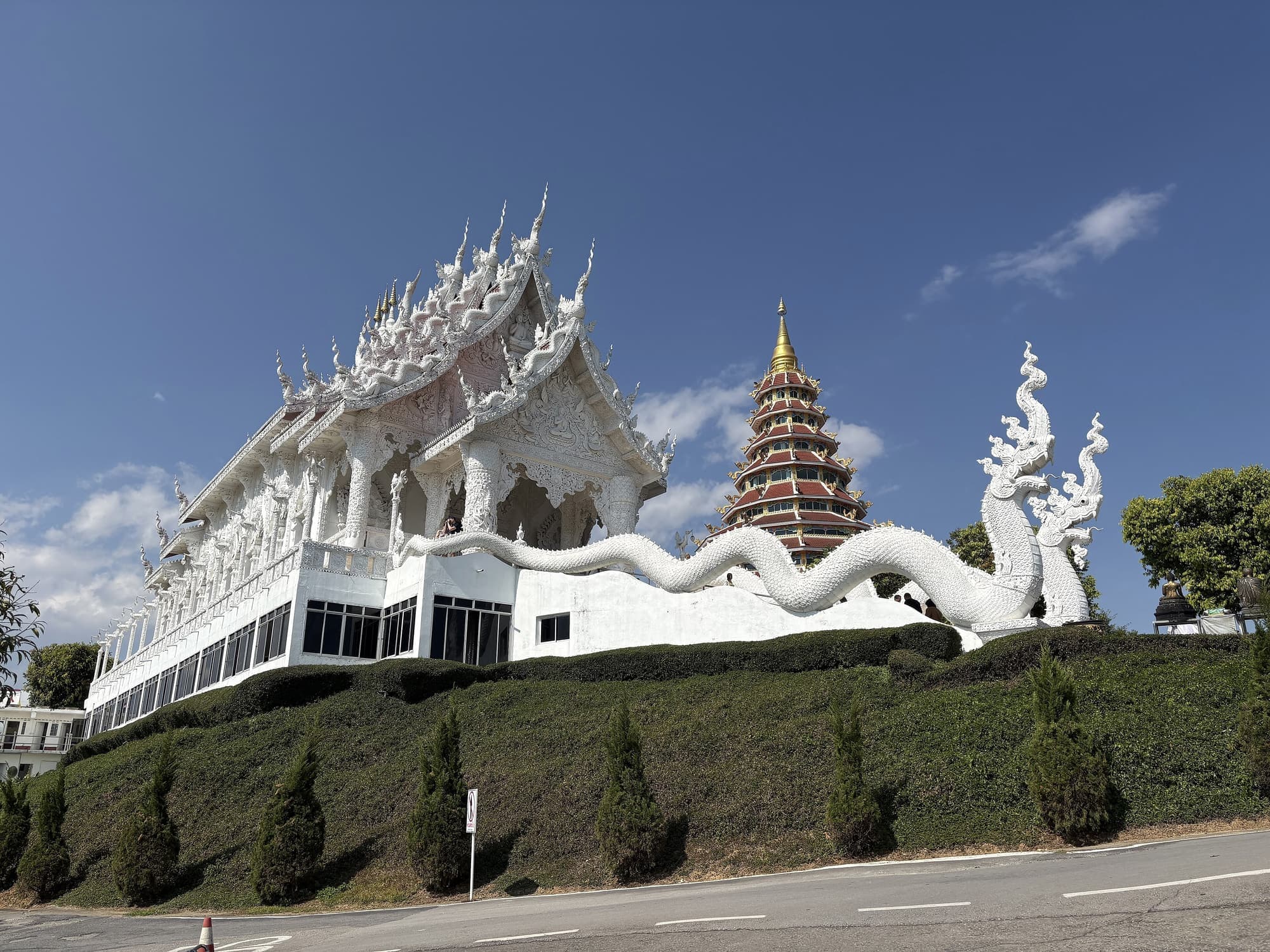 White temple hall with dragon stair and nine-tiered pagoda at Wat Huay Pla Kang