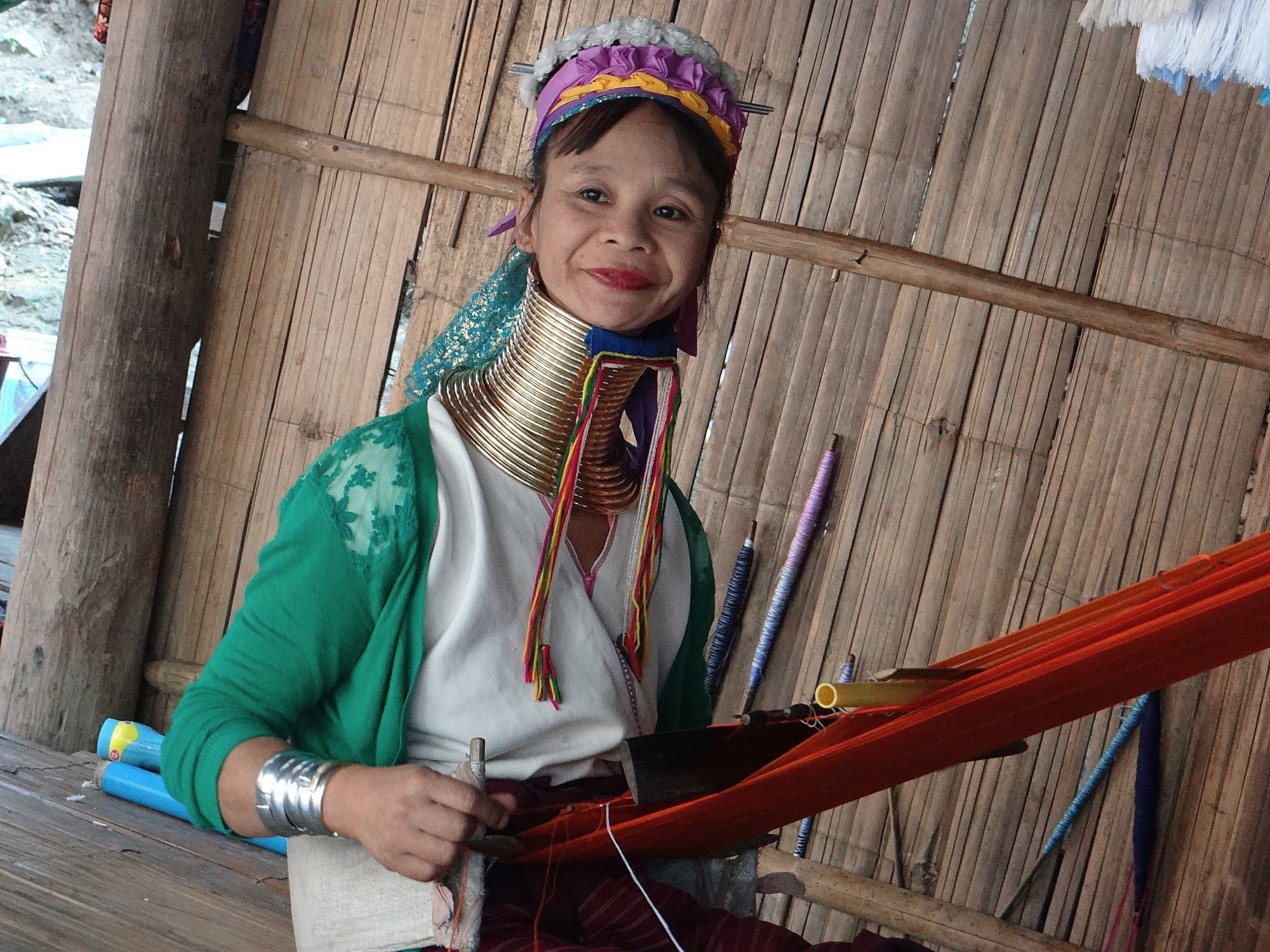 A Kayan woman wearing brass neck rings weaving on a backstrap loom